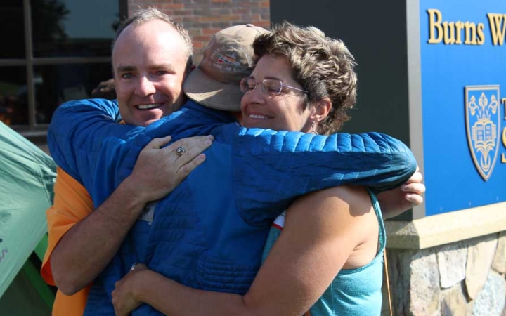 Two parents embrace their child at the family seminar of an outward bound intercept course. 